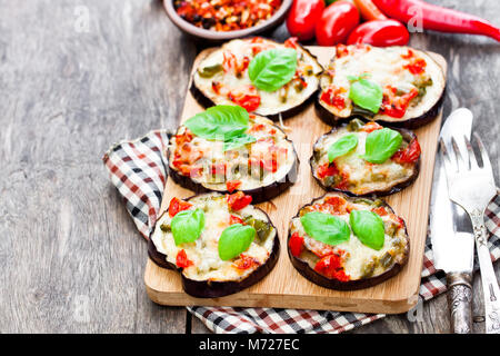 Baked  eggplant with cheese and tomatoes on cutting board Stock Photo