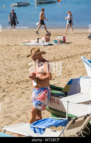 Elderly man using mobile phone on beach Stock Photo