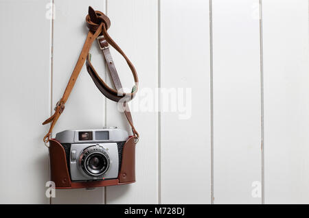 old retro style 35mm rangefinder camera hanging on painted wooden wall Stock Photo