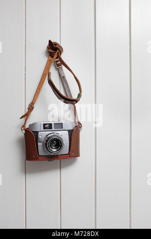 old retro style 35mm rangefinder camera hanging on painted wooden wall Stock Photo