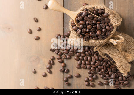 roasted coffee beans in wood scoop and on wood background, top view and copy space for text Stock Photo