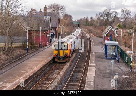 A Class 156 diesel multiple unit train passing through the rural station at Sankey in Cheshire. East Midlands Trains