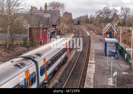 A Class 156 diesel multiple unit train passing through the rural station at Sankey in Cheshire. East Midlands Trains