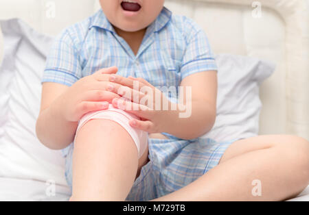 Obese fat boy suffering from knee pain and sit on bed, Healthy problem Stock Photo