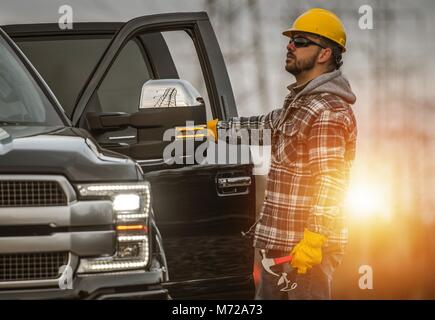 Energy Sector Worker in the Field. Electrical Infrastructure Construction Technician and His Company Truck. High Voltage Lines Maintenance. Stock Photo