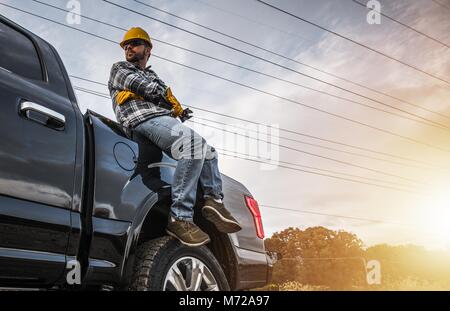 Caucasian Construction Worker Relaxing on His Pickup Truck. Freelance Handyman Worker Stock Photo