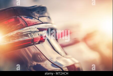 Row of New Cars. Vehicles Rear Closeup. Car Dealership Lot. Automotive Theme. Stock Photo