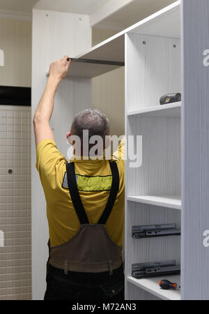 the master installs a wardrobe in apartment Stock Photo