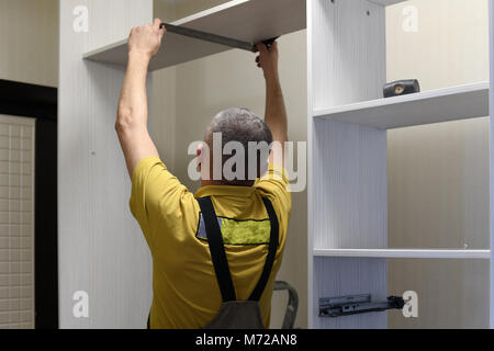 the master installs a wardrobe in apartment Stock Photo