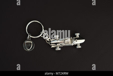 Silver-chrome keychain with an  old super fast model on leather background Stock Photo