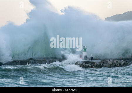 Fishermen braving enormous waves that are seen here crashing up against the breakwater of Kalk Bay harbour in Cape Town, South Africa. Stock Photo