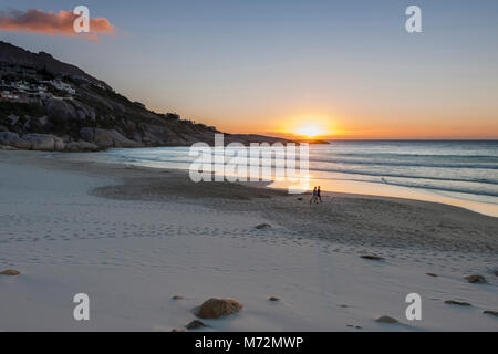 A couple walking on Llundudno beach in Cape Town at sunset. Stock Photo