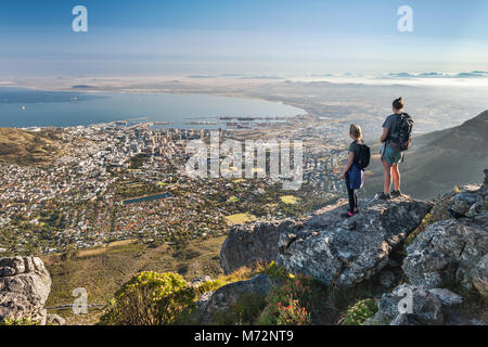 Two hikers admiring the view of Cape Town from a viewpoint along the India Venster hiking path on Table Mountain. Stock Photo