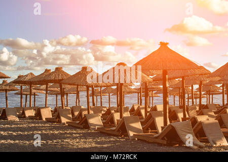 Sun loungers and umbrellas are on the beach in Budva, Montenegro. Sun flare Stock Photo