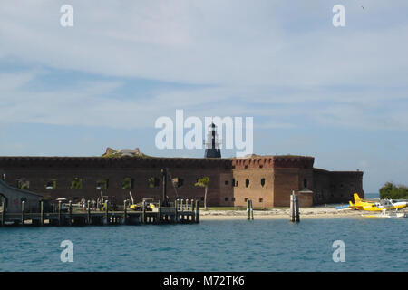 Fort Jefferson with Harbor light . DRTO 2006  This image shows the main dock at Fort Jefferson in Garden Key harbor. To the right is a commercial seaplane, and behind that is Bastion C, atop which sits the iconic 1876 boiler plate harbor light. Stock Photo