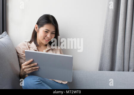 asian woman smiling while using digital tablet at home Stock Photo