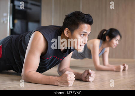 young asian couple doing plank in gym Stock Photo