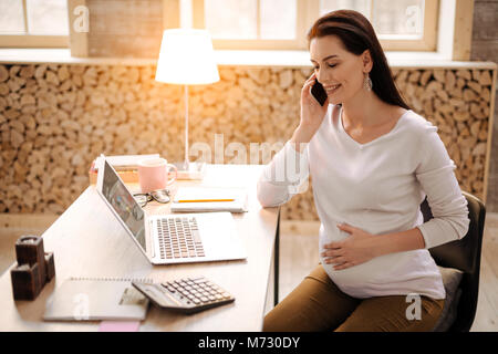 Optimistic pregnant woman using phone Stock Photo