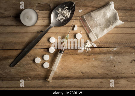 Drugs, powder, spoon, and tablets on rustic wooden background. Drug addiction concept background with space for text Stock Photo
