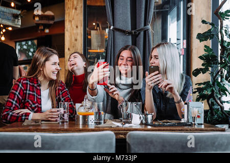four friends look at the phone and laugh Stock Photo