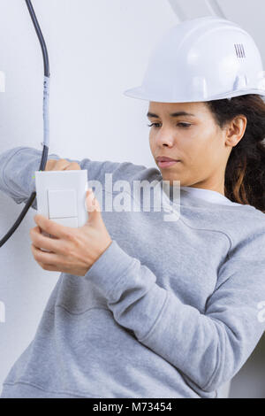 Female electrician fitting light switch Stock Photo