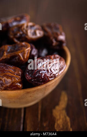 Fresh dates fruit in wooden bowl on wooden background Stock Photo