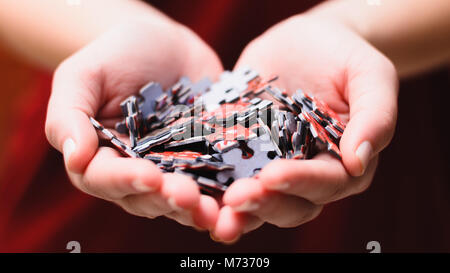 Jigsaw Puzzle Game: Hands together of a woman holding a bunch of puzzle pieces. Hands on a heart shape. Stock Photo