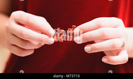 Jigsaw Puzzle Game: Hands of a woman holding and matching two pieces of a puzzle. Stock Photo