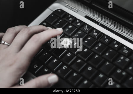 Hand of a woman over a laptop with a missing keyboard key. Broken keyboard key, need for maintenance. Stock Photo