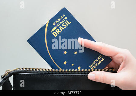 Brazil - March 02, 2018: Woman hand taking the Brazilian passport out of the bag. Stock Photo