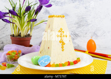 Traditional curd Easter cake with candied fruits and spring flowers crocus on the holiday light background. Easter cottage cheese dessert. Easter fest Stock Photo