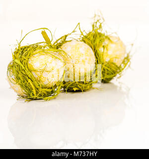 thre Easter egg decoraiton in row wrapped in hay on white Stock Photo