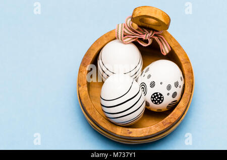 three decorated hen eggs in a basket from above on blue background Stock Photo