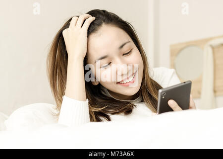 women sleep on bed in bedroom and holding smart phone Stock Photo