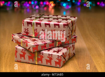 Wrapped christmas presents on a table with fairy lights in the background Stock Photo