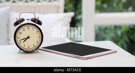 Old clock  and tablet on the table in living room Stock Photo