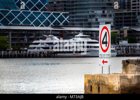 A 4km speed sign at Pyrmont, one of the may coves & inlets within Sydney Harbour, Australia. In the background are office towers and cruise boat Stock Photo