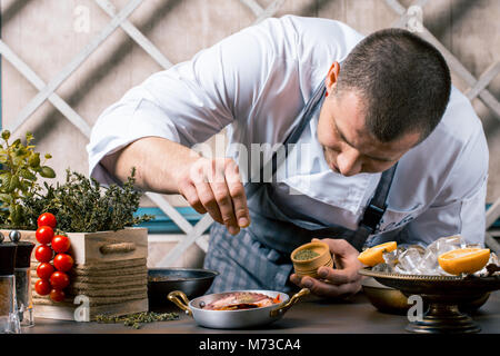 Chef sprinkling spices on dish from octopus in commercial kitchen. Gourmet Restaurant Stock Photo