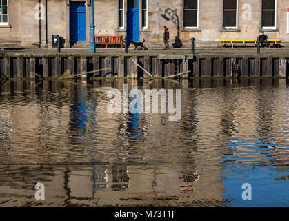 The Shore, Leith Harbour, Leith, Edinburgh, Scotland, United Kingdom, 8th March 2018. UK Weather: Spring weather with the sun creating lovely reflections in the Water of Leith. Reflections of Leith Customs House. A man walks his dog and a man rests on a bench with a coffee in the sunshine Stock Photo