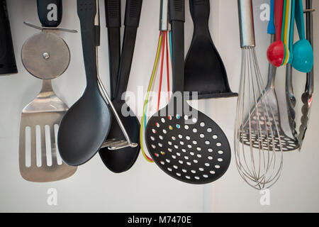 variety of kitchen utensils hanging on a rack in a kitchen in the uk Stock Photo