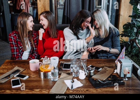 four friends in the cafe look at the camera and laugh Stock Photo
