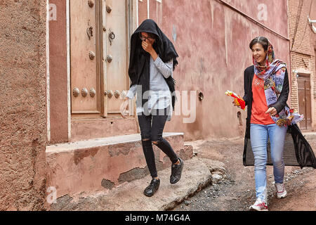 Abyaneh, Iran - April 26, 2017: two cheerful girls-tourists in hijabs walk around the traditional village in the mountains. Stock Photo