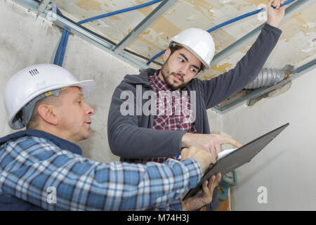 builders fastens profile using cordless screwdriver Stock Photo