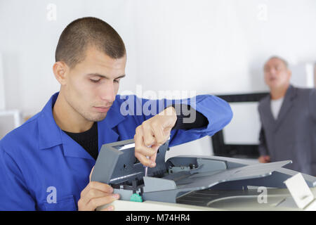 young apprentice man fixing photocopier Stock Photo