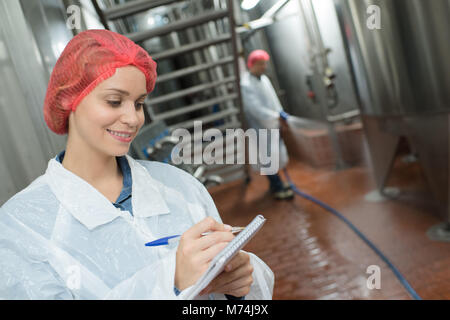 female factory worker writing notes on clipboard Stock Photo