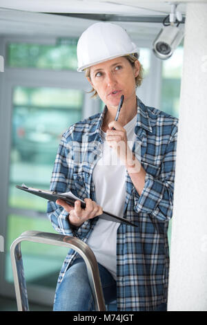 female technician adjusting cctv camera on wall Stock Photo