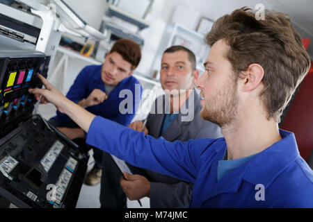 male apprentices trying to repair the office printer Stock Photo
