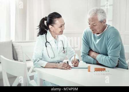 Pretty pleasant nurse giving advices and writing it. Stock Photo