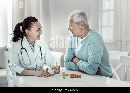 Pleasant mature nurse having conversation and smiling. Stock Photo