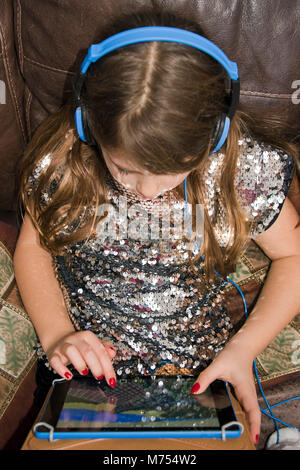 Vertical portrait of a young girl playing on her laptop. Stock Photo